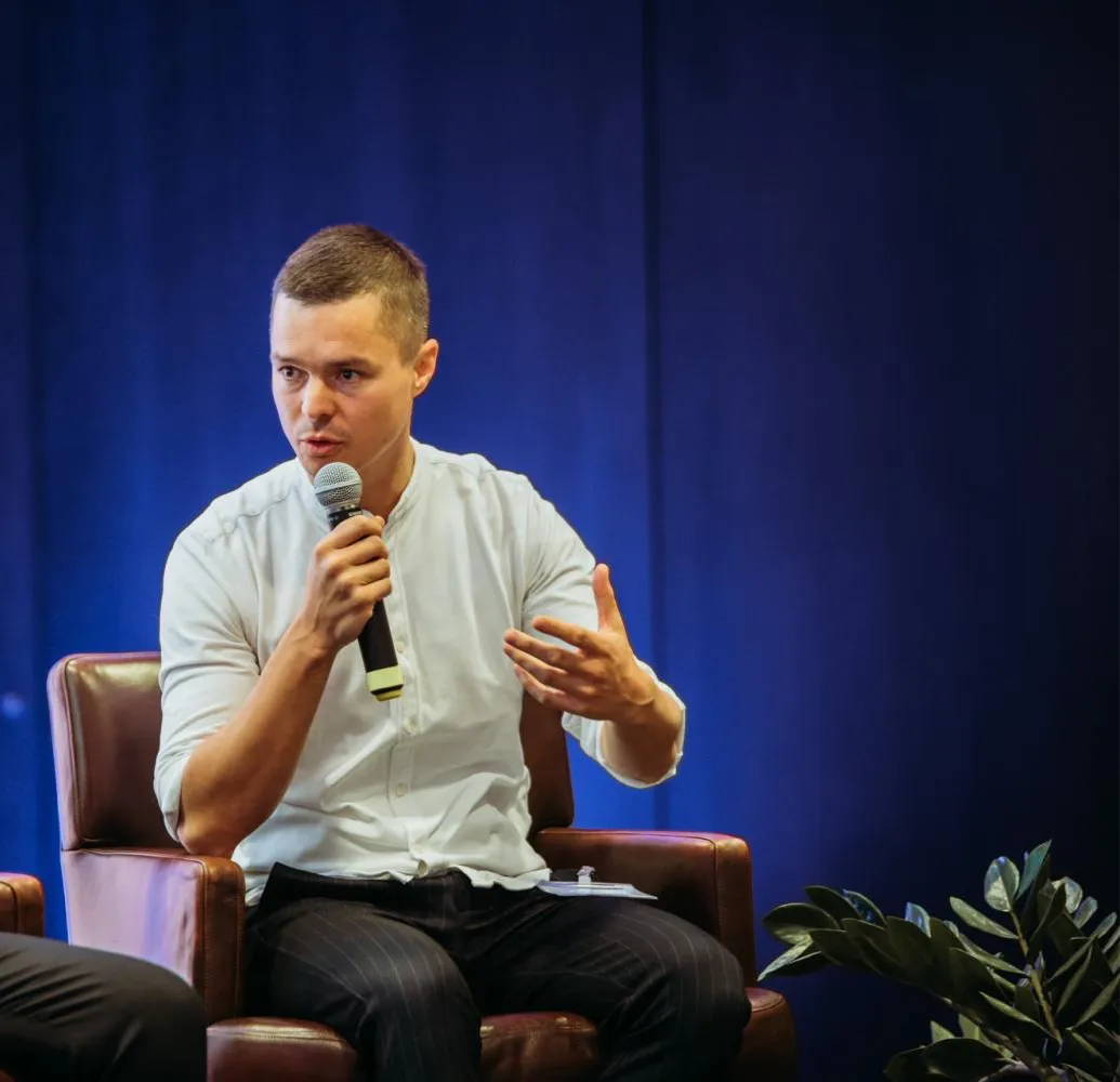 Tobias Kilga on stage, speaking into a microphone.
